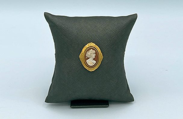 A pin/broach on display with a grey background.