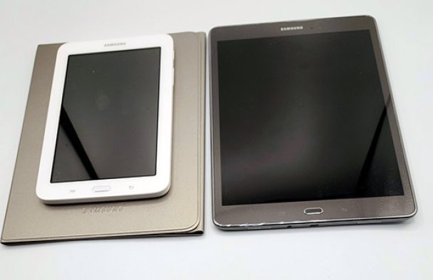 Two tablets, one white and one black, sit on a table.