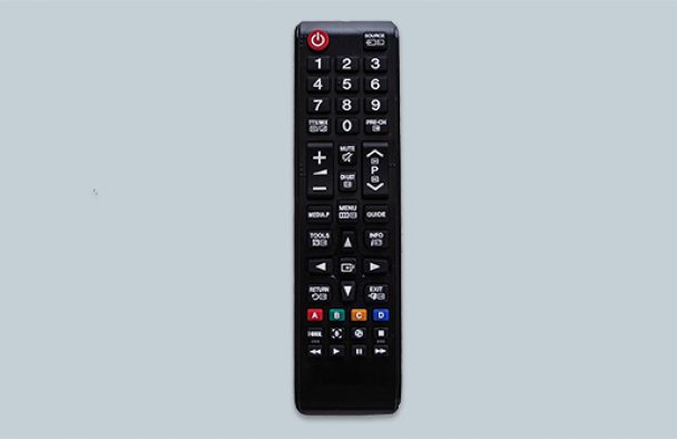 A black remote standing up sits on a table with a grey background.